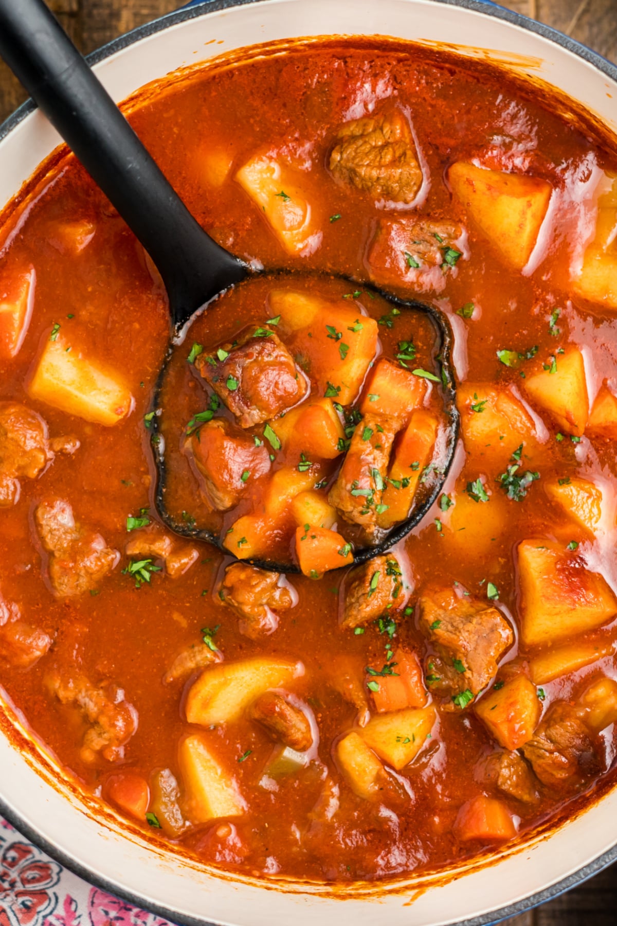 A ladle scooping out some beef stew.
