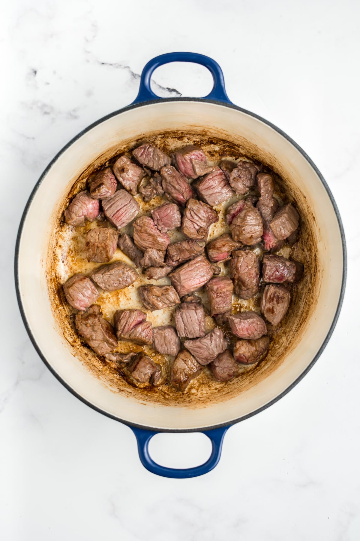Stew meat pieces browning in a pot.