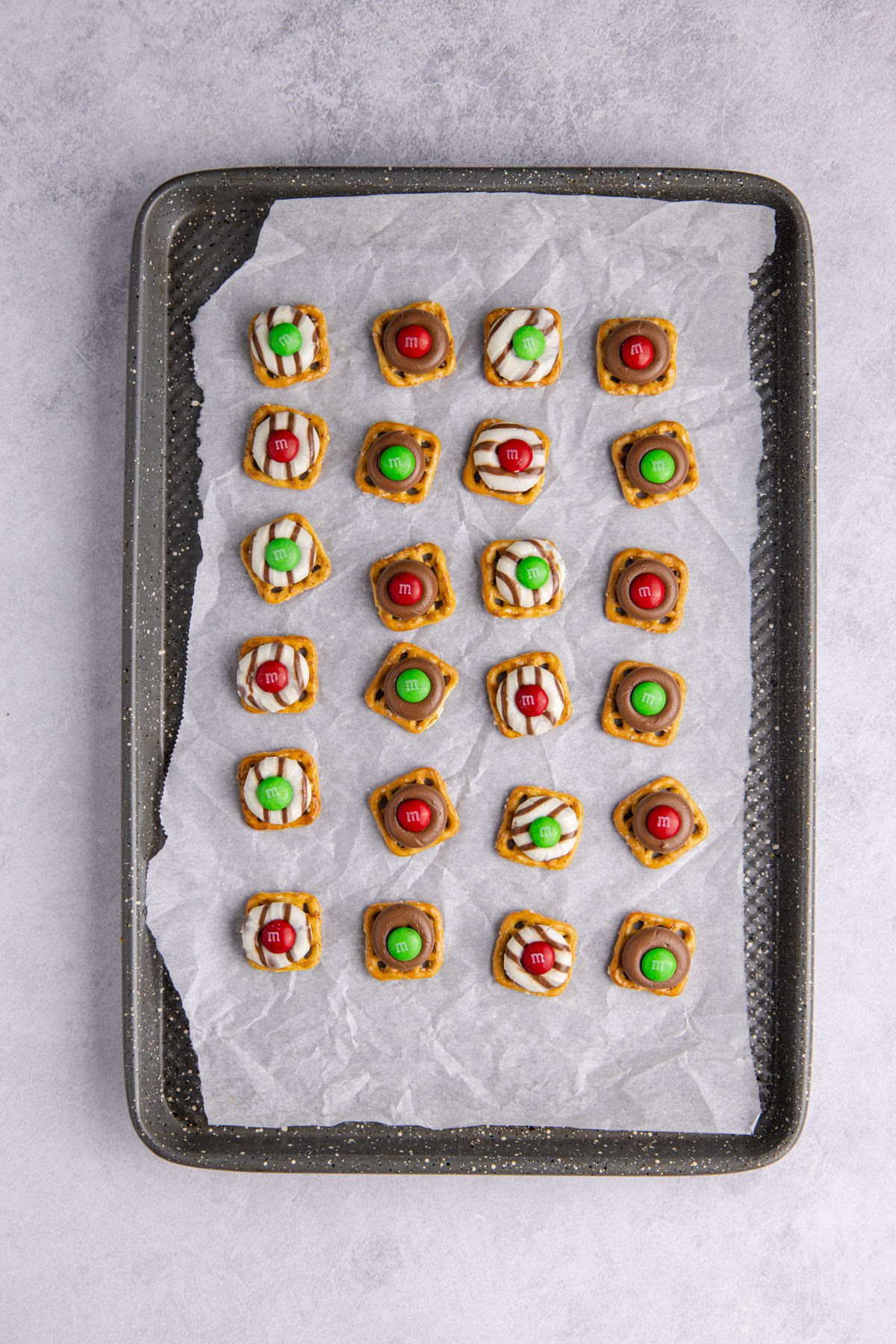 M&Ms placed on top of each pretzel and chocolate. 