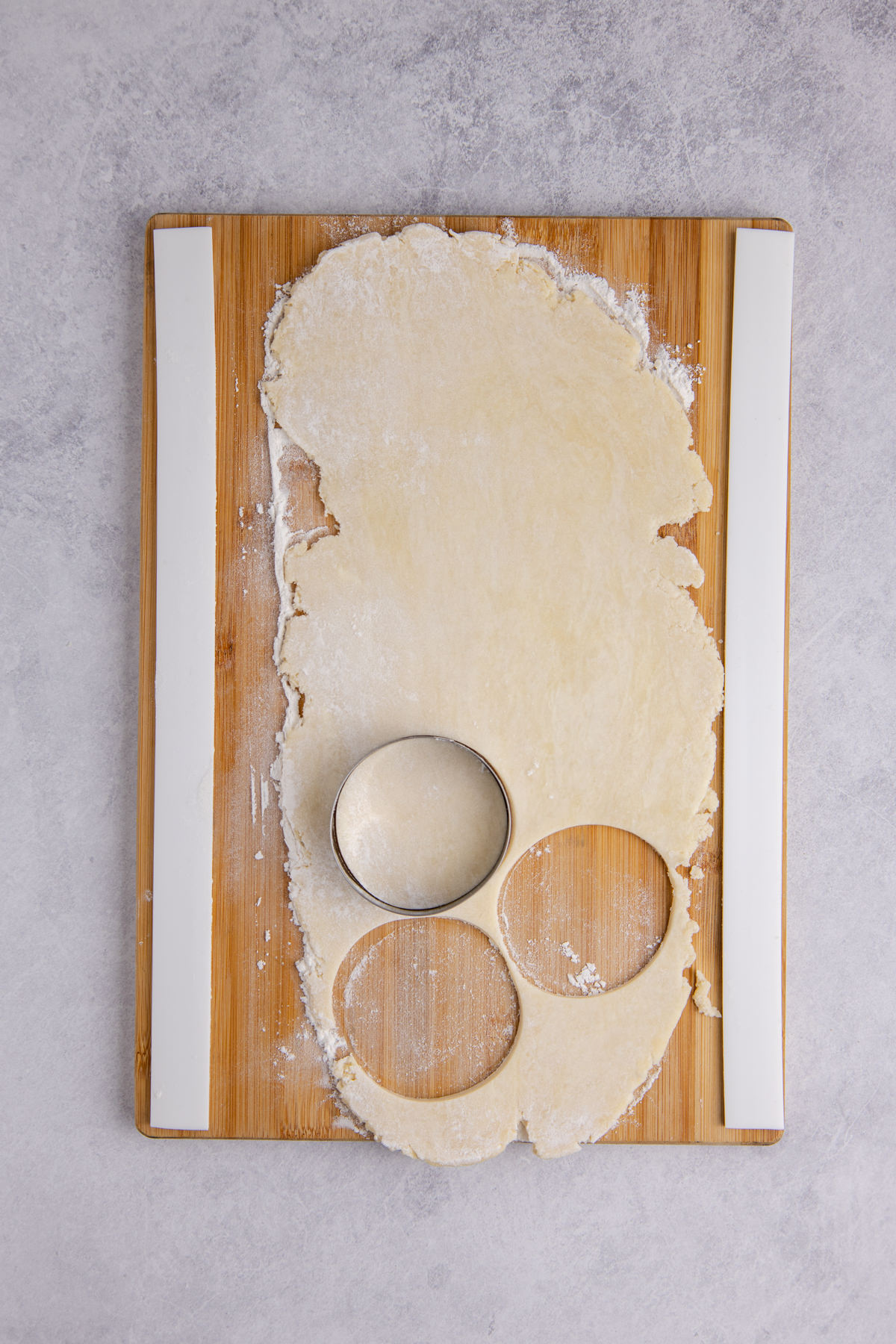 Dough rolled out onto a flat surface and forming cut outs. 