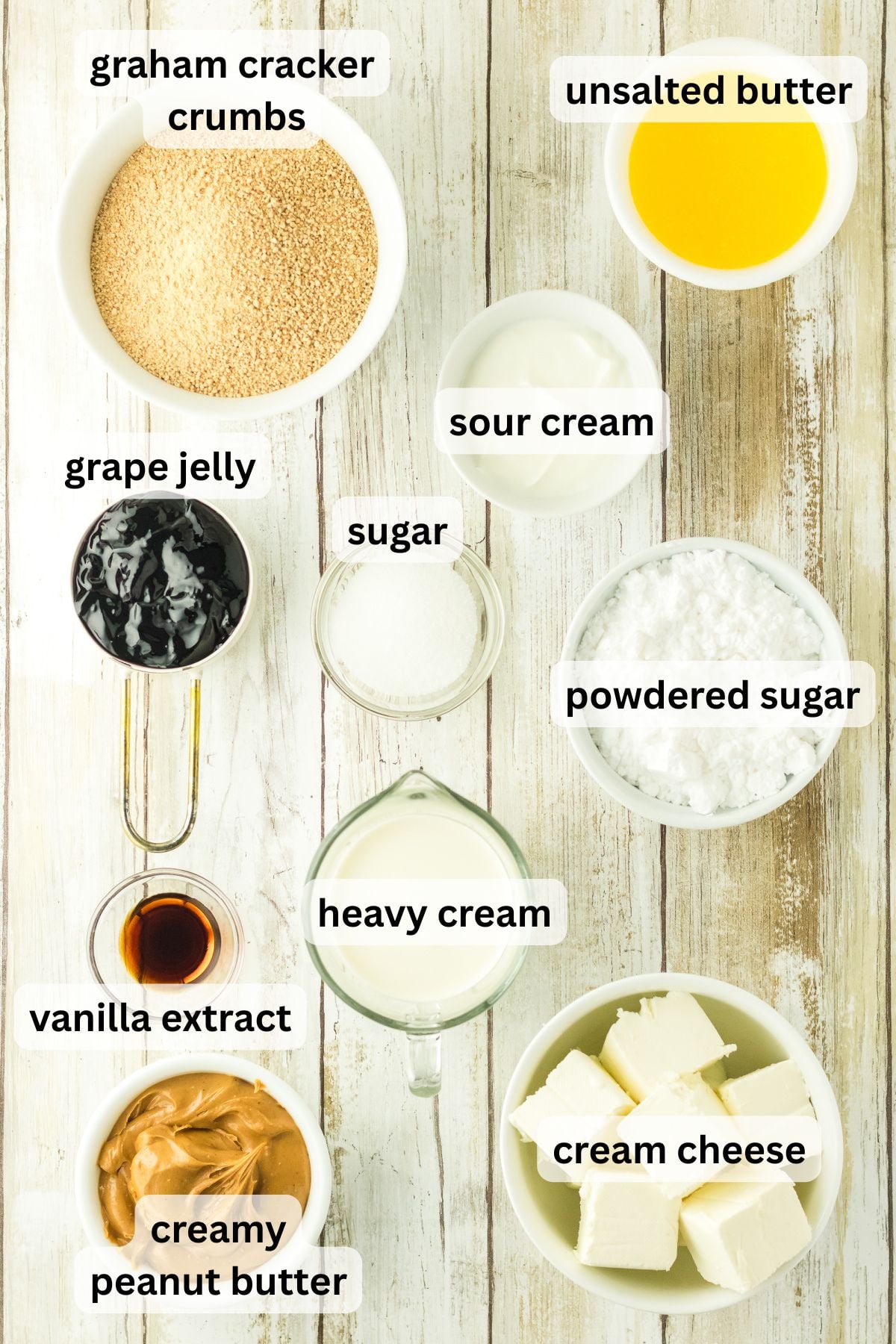 Ingredients to make these pbj cheesecake bars in bowls on a table.