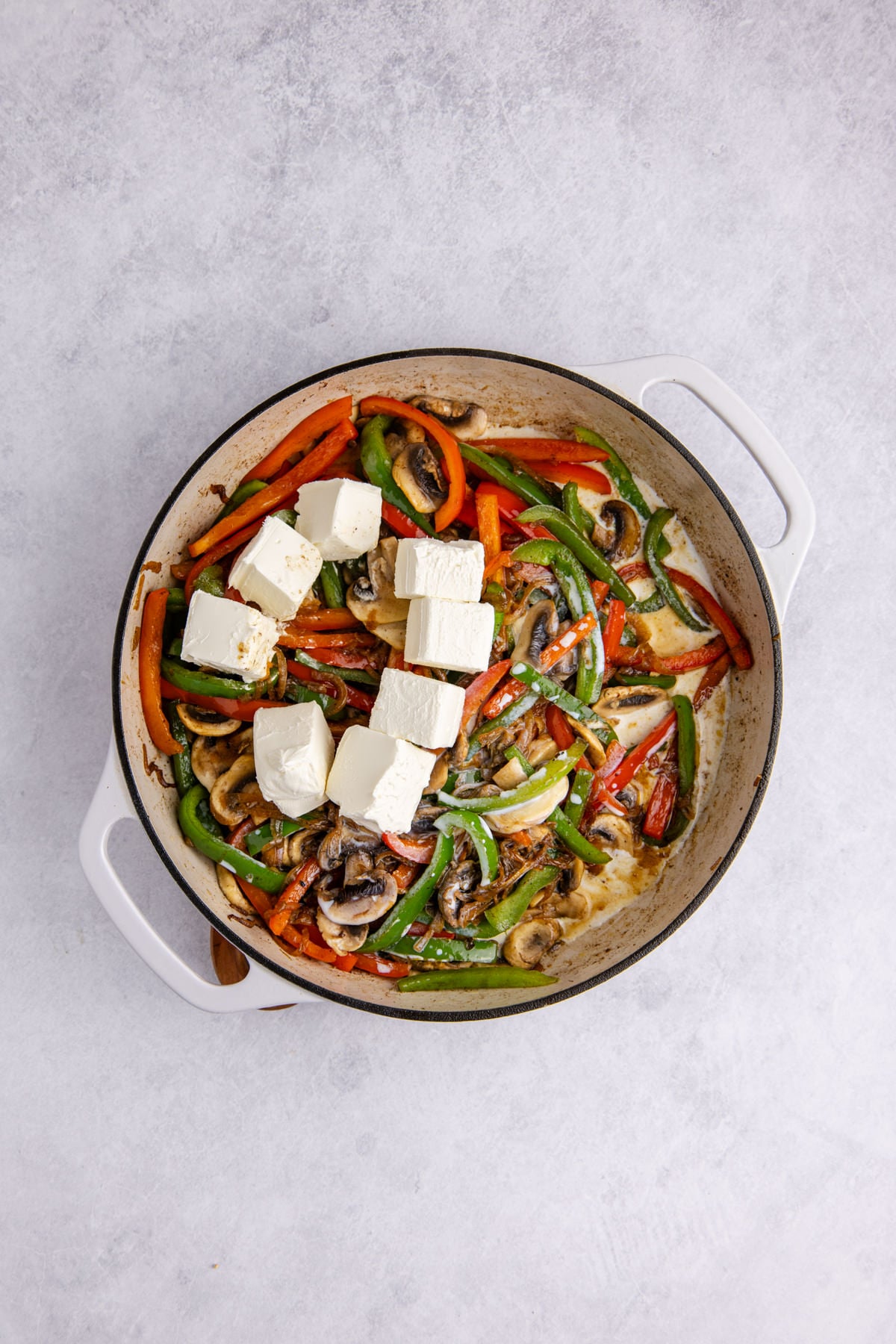 Peppers, mushrooms, milk and cream cheese added to the skillet.