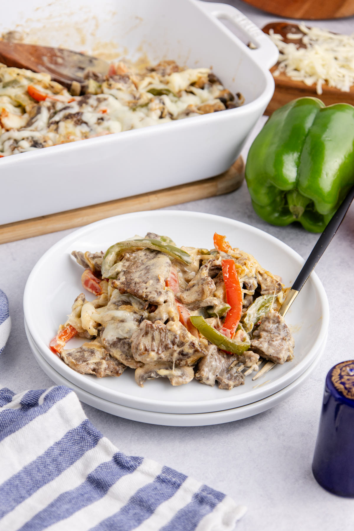 Casserole with steak, onions, peppers and cheese on a plate.