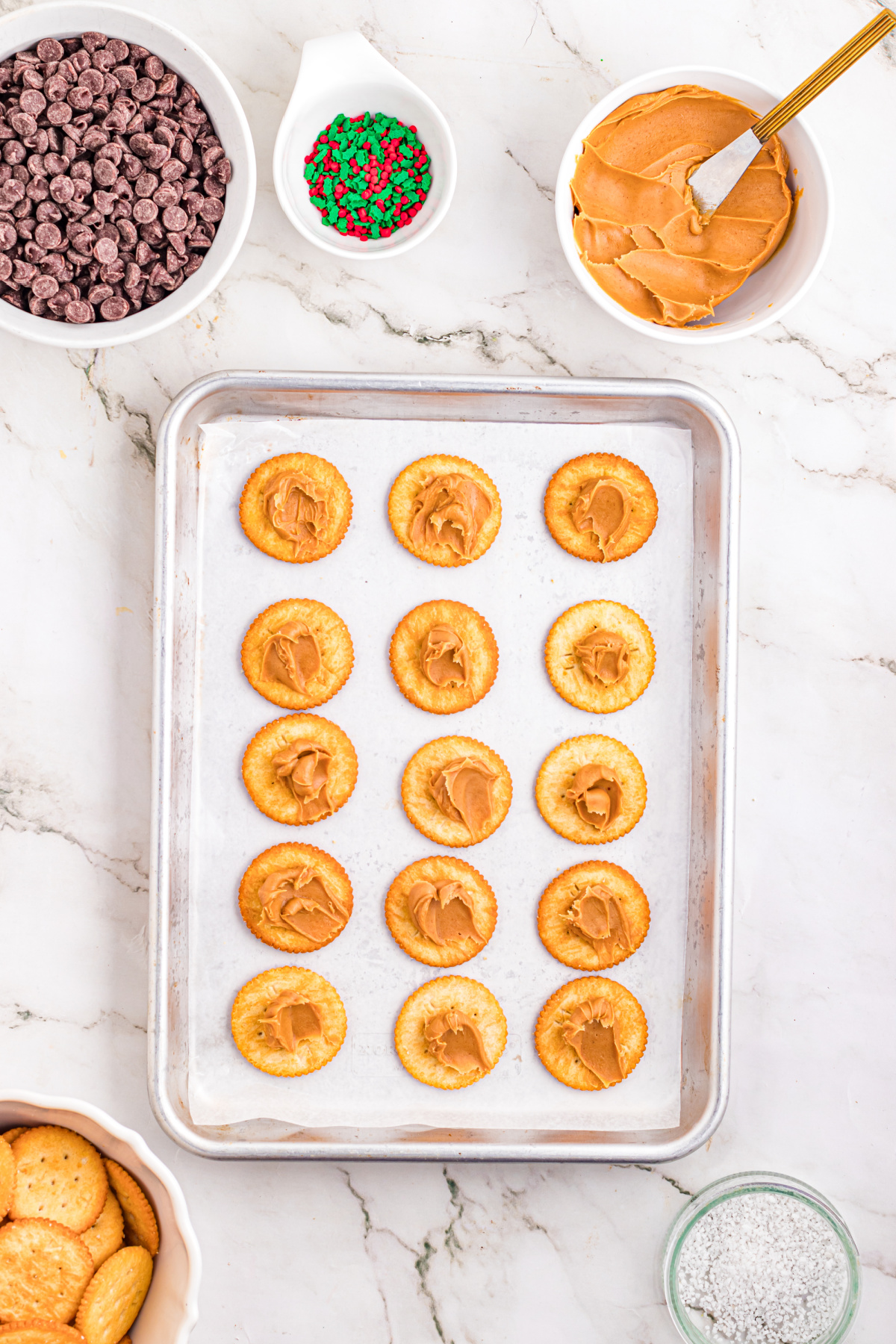 Ritz crackers arranged on a cookie sheet peanut butter on top.