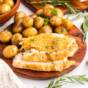 A baked whole chicken in the oven sliced up on a plate with potatoes.