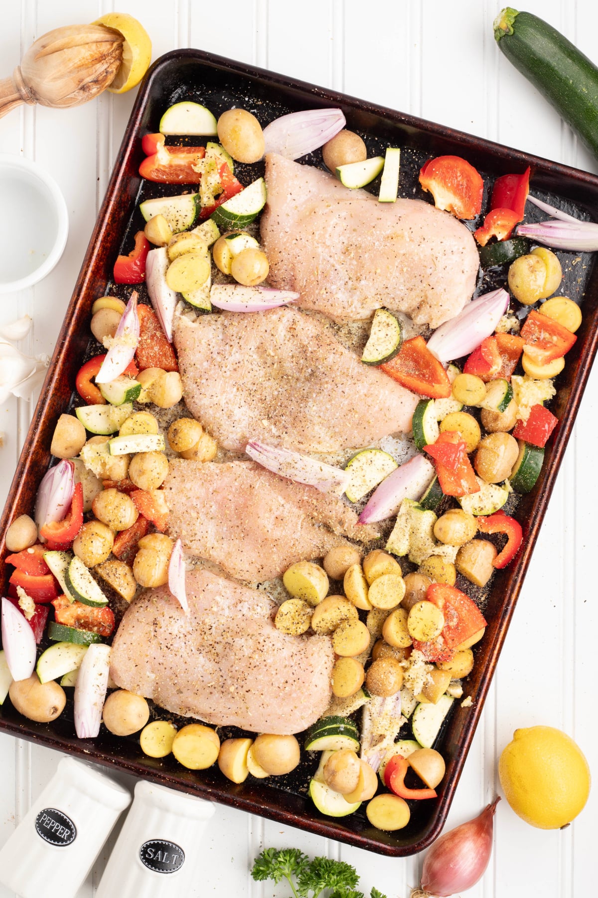 Veggies, potatoes, and chicken breasts on a sheet pan.