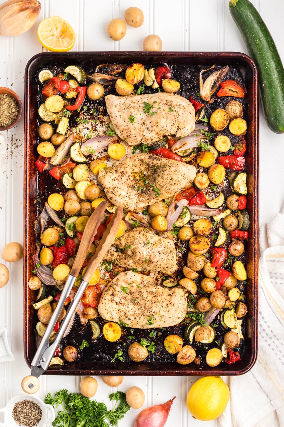 Veggies, potatoes, and chicken breasts cooked on a sheet pan.
