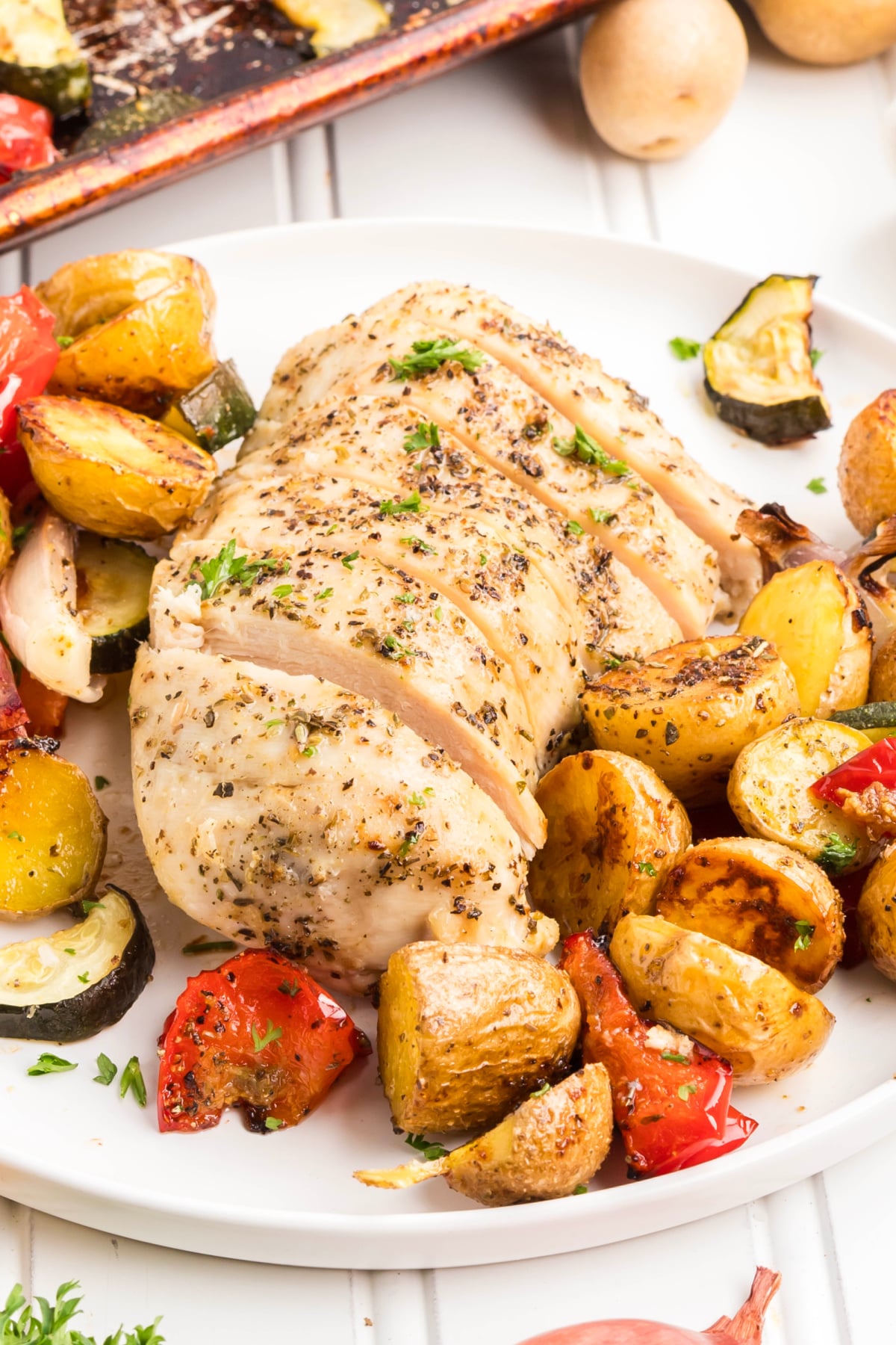 A chicken breast with potatoes and veggies on a plate.