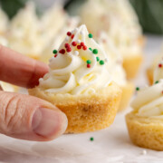 Christmas sugar cookie cups being held up off of a plate.