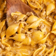 Taco hamburger helper being scooped out with a wooden spoon.