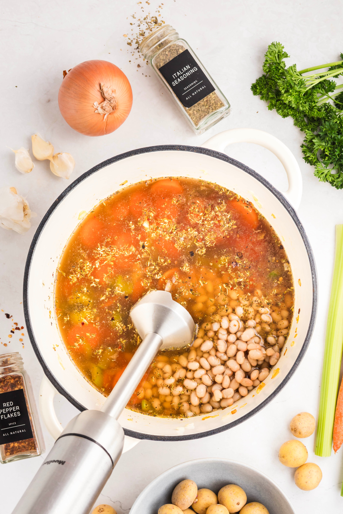 Immersion blender blending the ingredients in a pot.