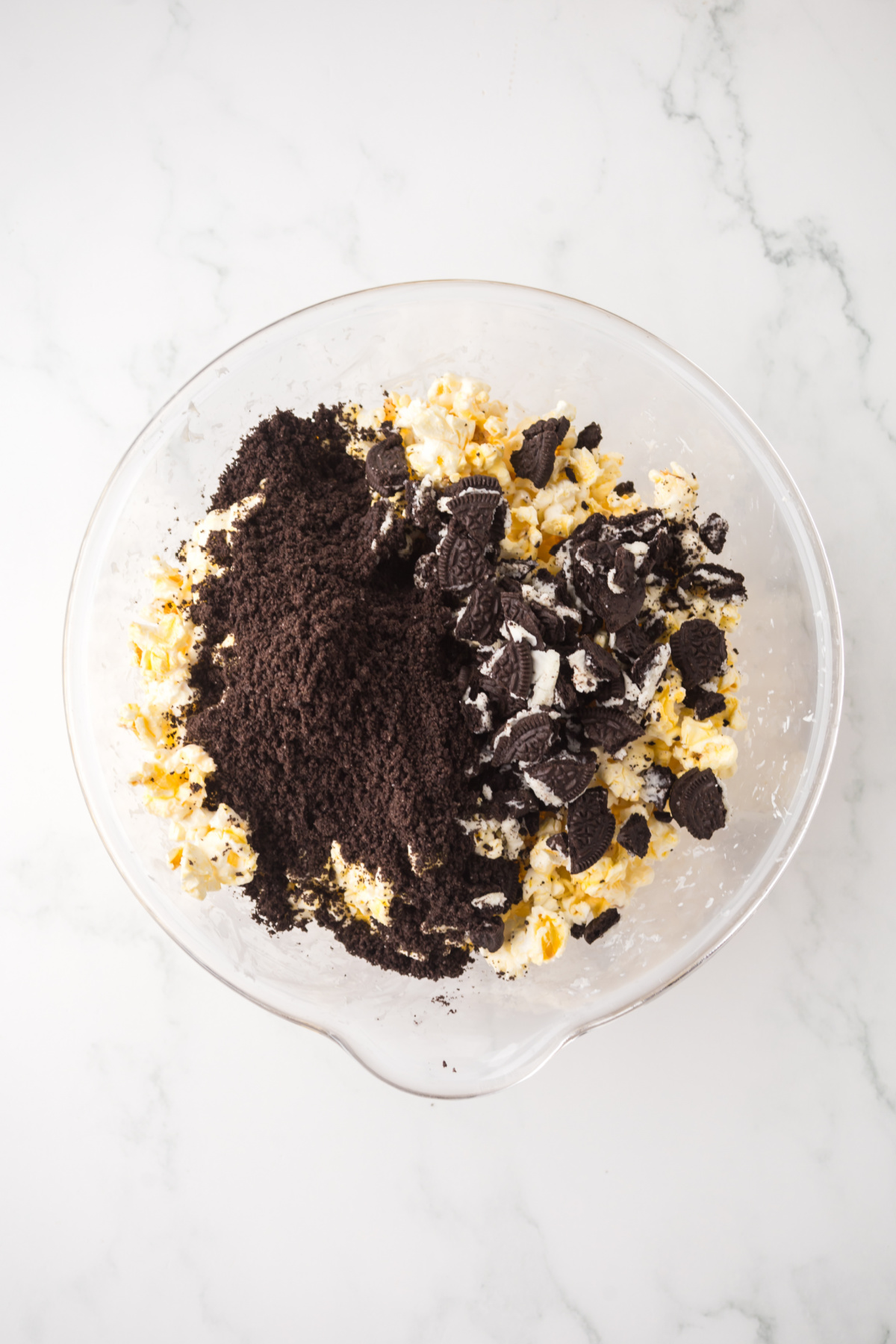 A bowl of popcorn coated in chocolate with Oreos added ready to be folded in.
