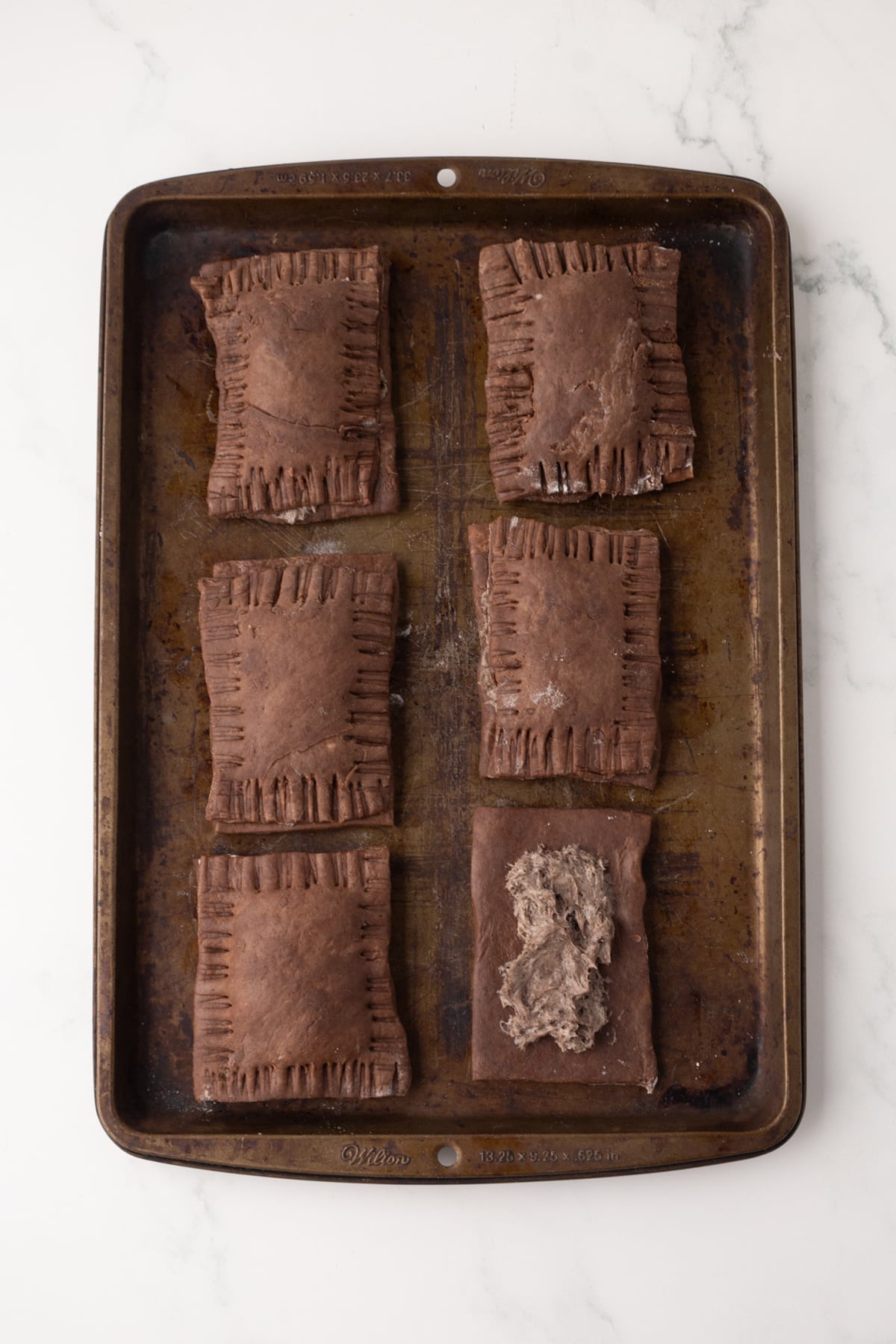 Filled poptarts ready to bake and one with filling showing waiting to be finished.