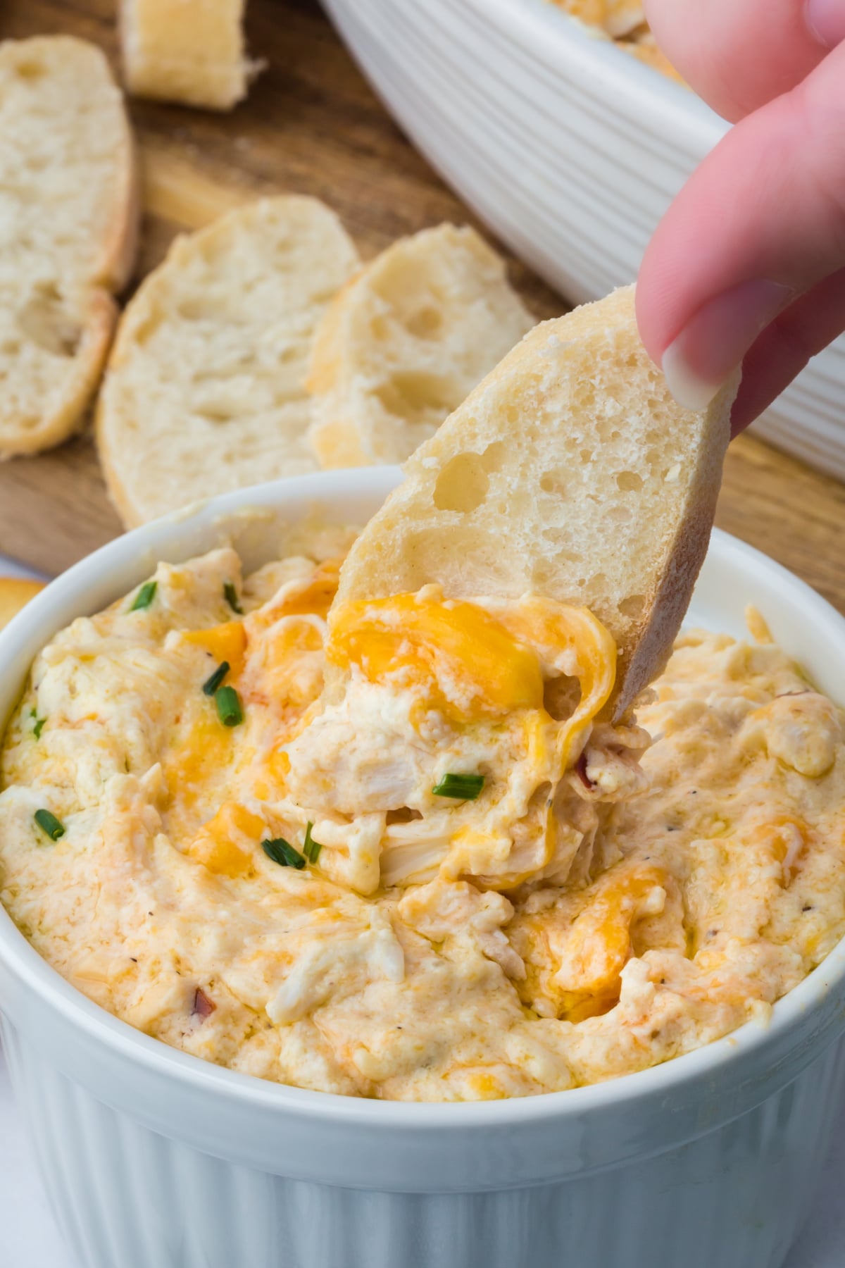 A slice of bread being scooped into crab dip.