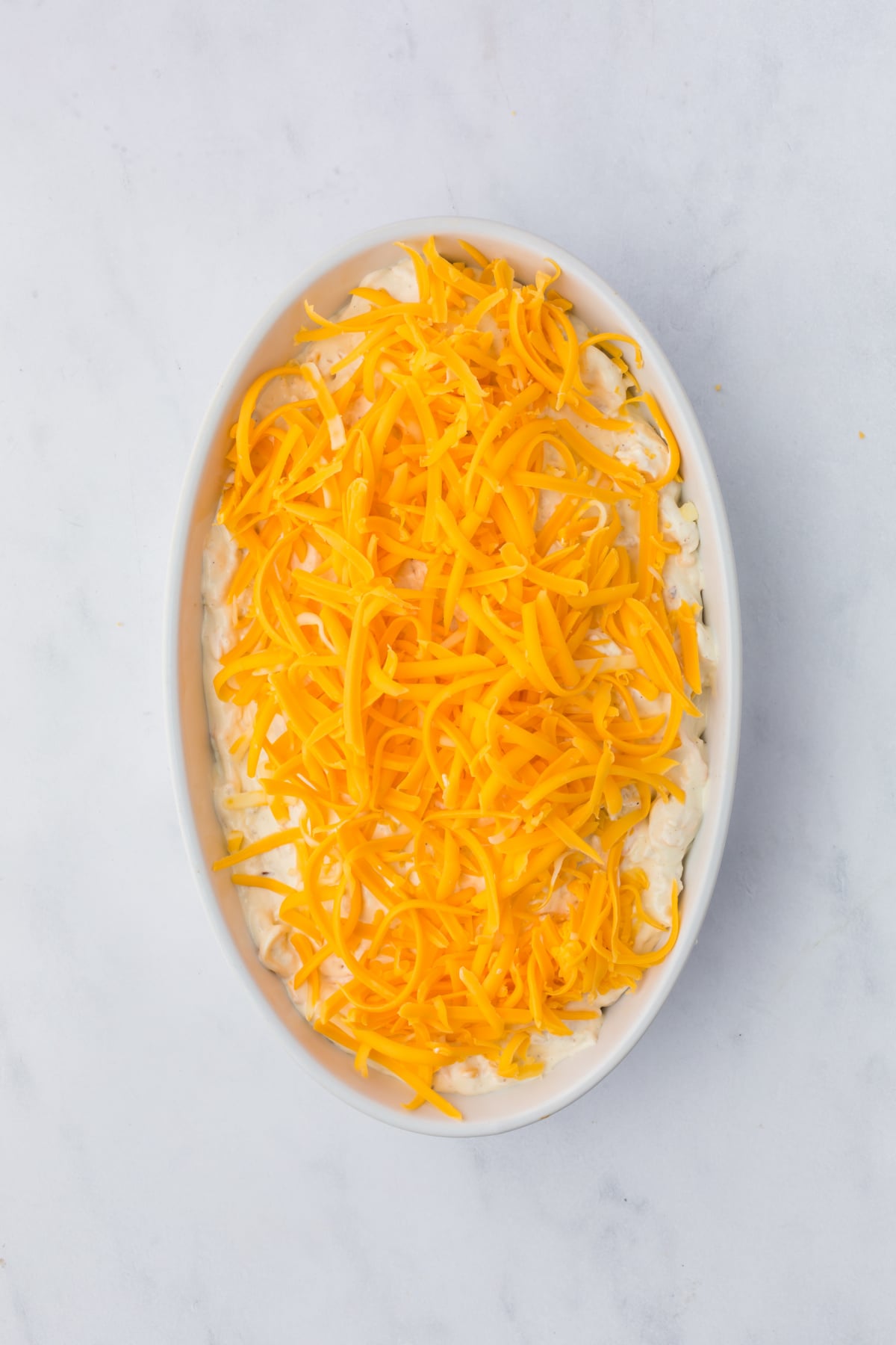 The dip transferred to a baking dish with cheese added to the top.