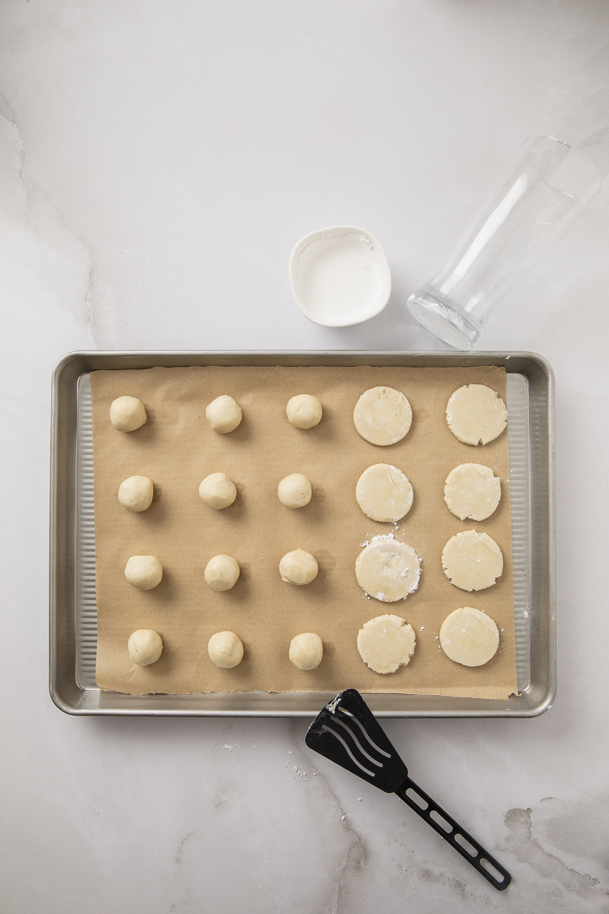 Balls of cookie dough pieces being flattened.