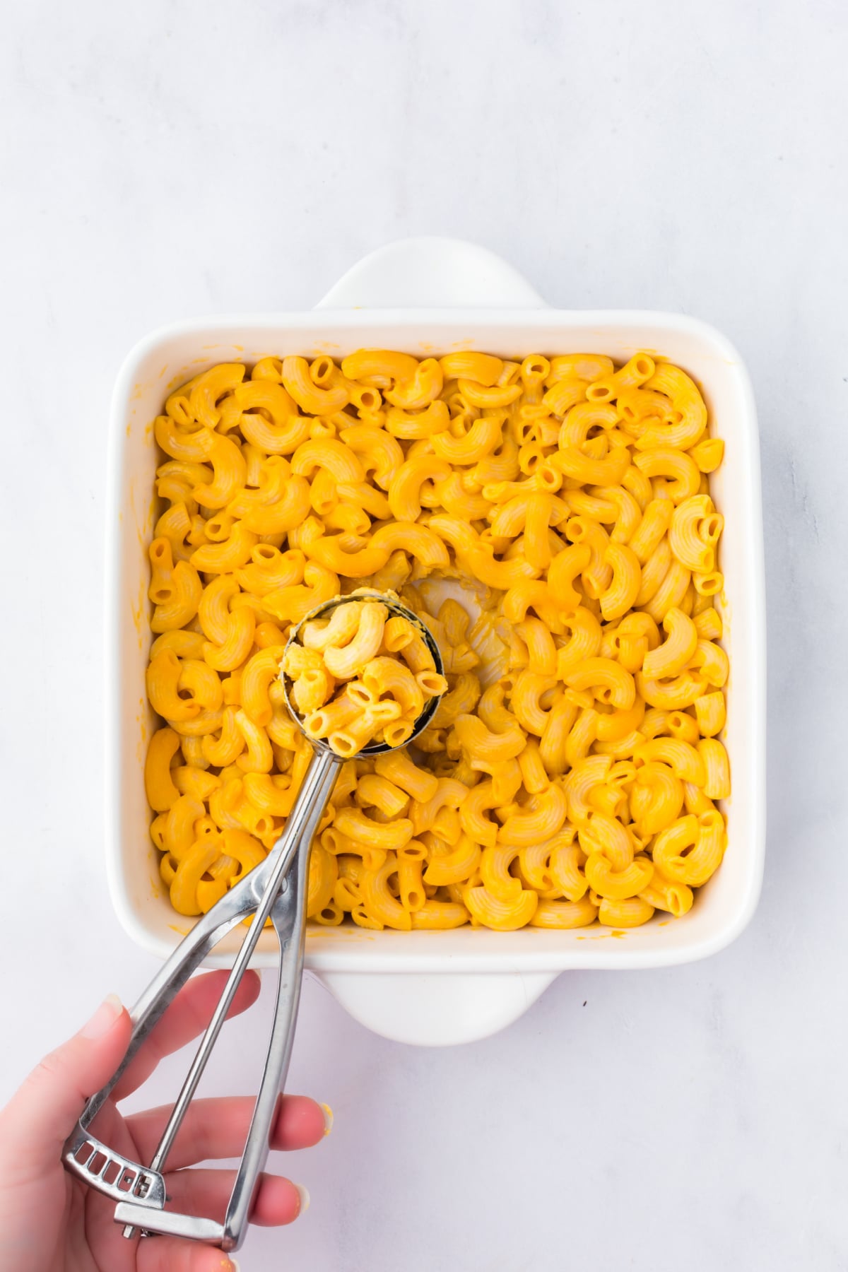 Chilled mac and cheese being scooped into balls.