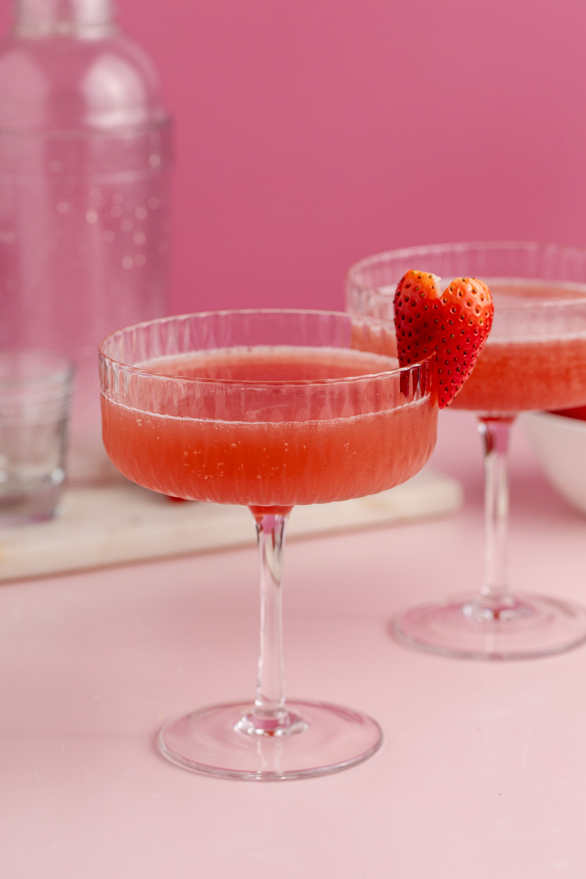 The drink poured into two cocktail glasses with a heart-shaped strawberry.