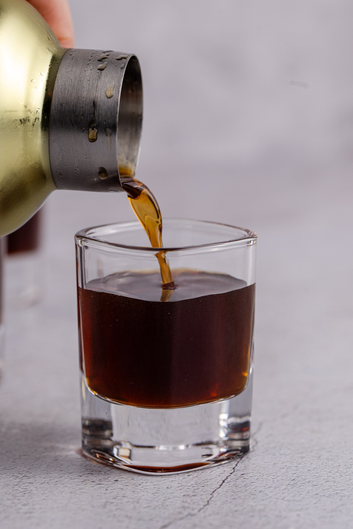 Cocktail shaker pouring into shot glass.