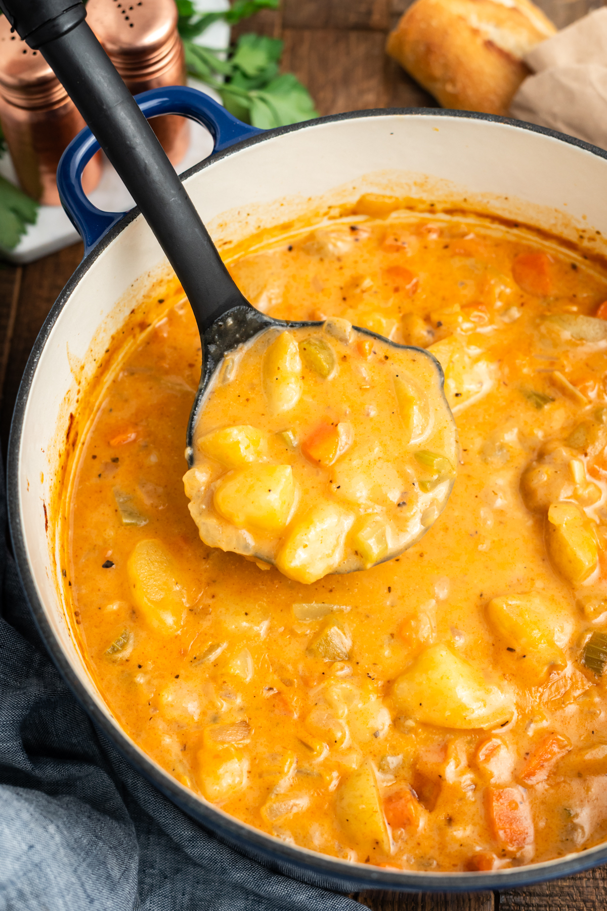 A ladle scooping out potato stew from a pot.