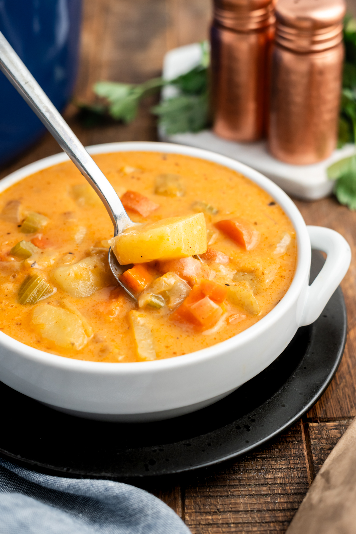 A bowl full of potato stew with a spoon taking some out.