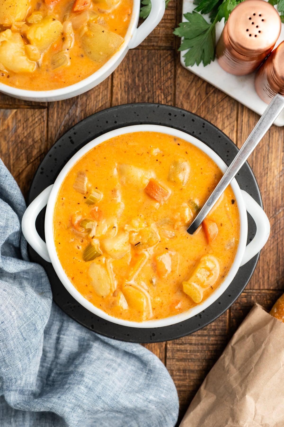 A bowl with potato stew and a spoon resting on the side in the bowl.
