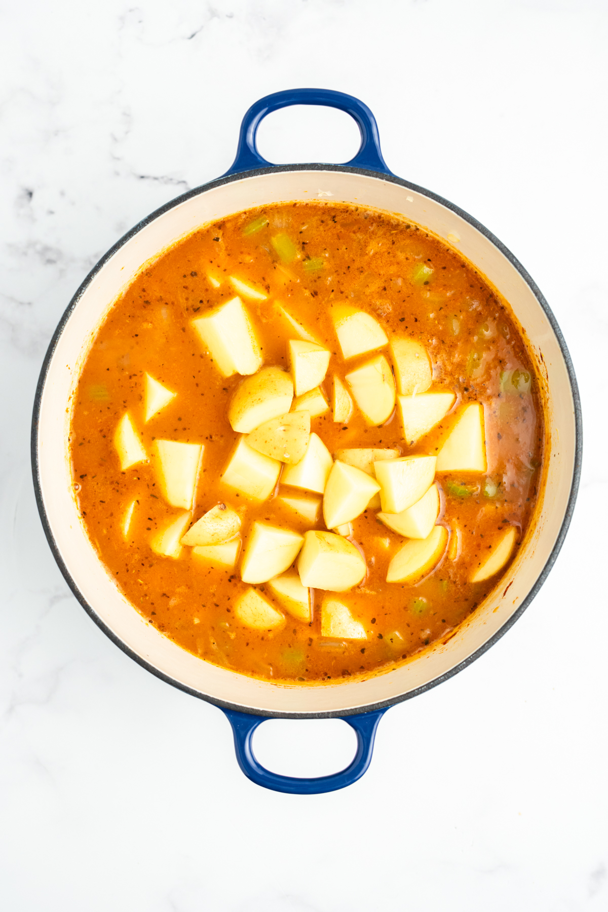 Potatoes, seasoning, and bay leaf added to the pot.
