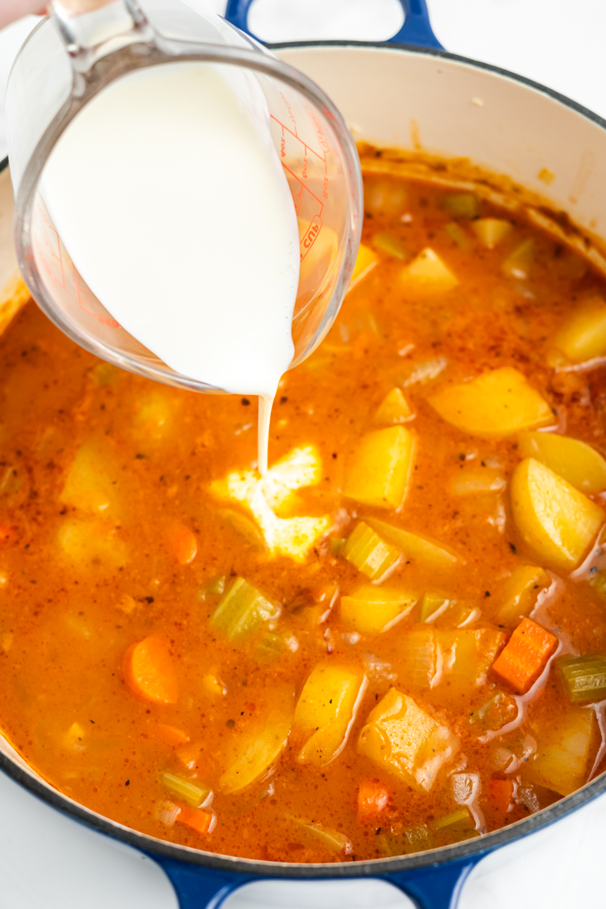 Heavy cream being poured into the stew.