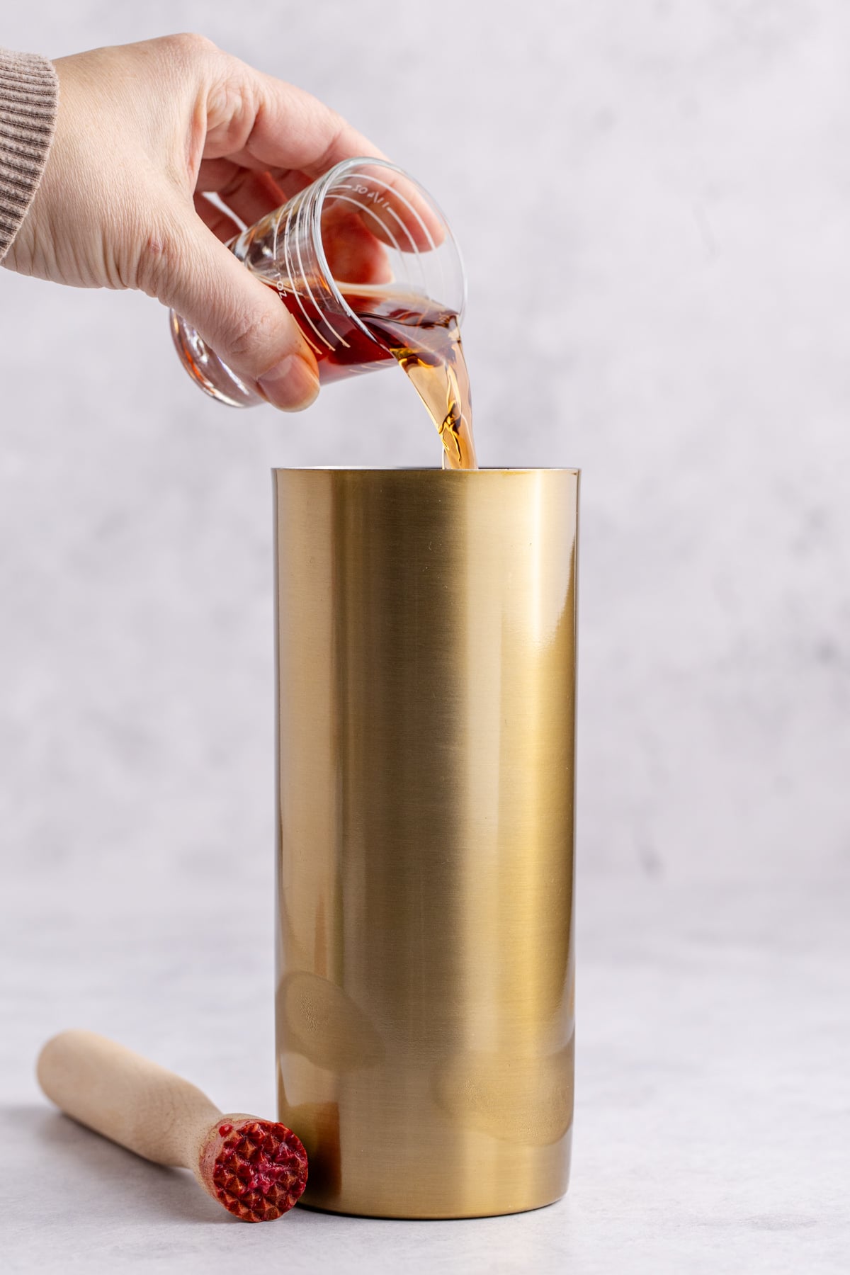 Muddled raspberries, ice and liquors being added to the cocktail shaker.