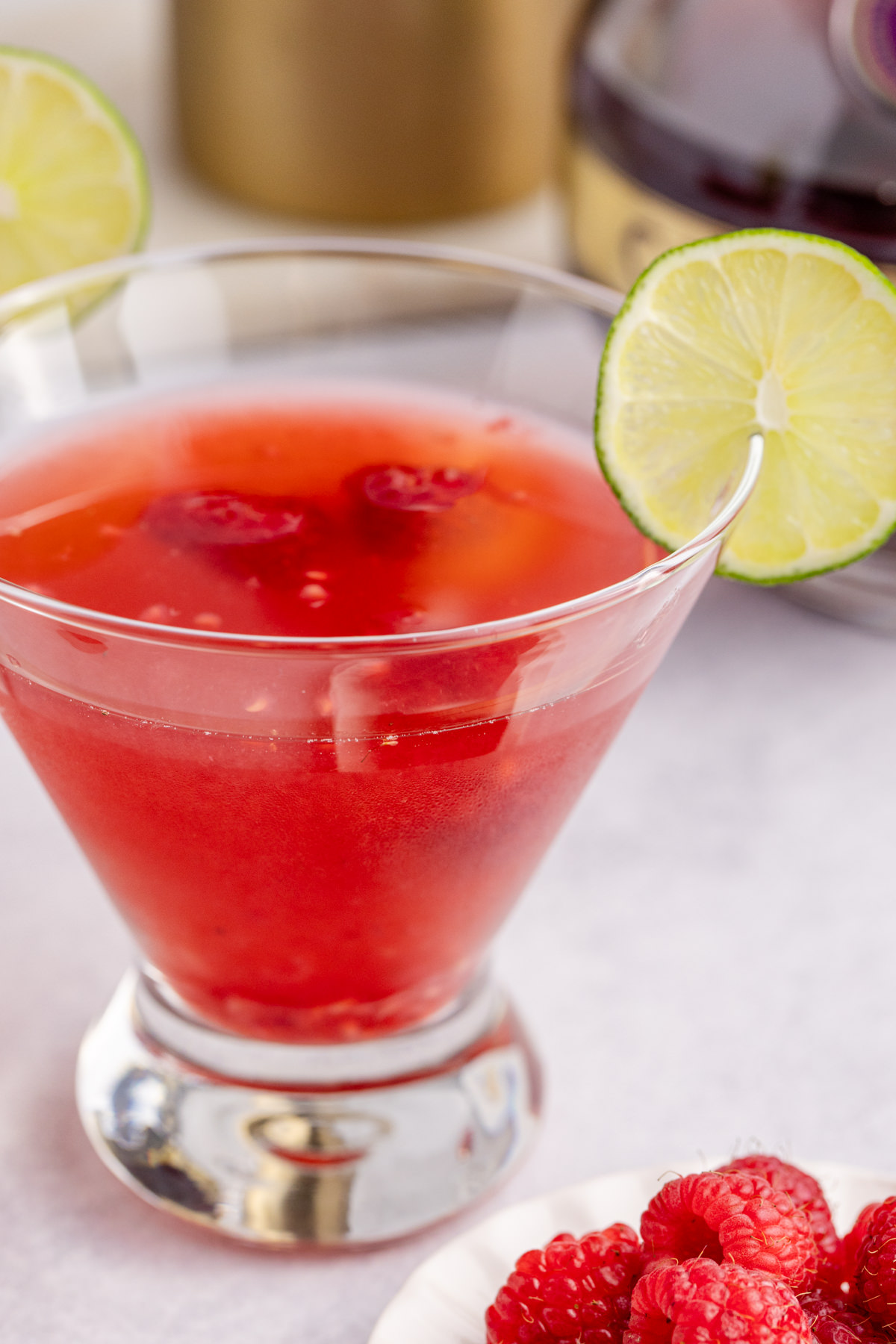 A glass filled with a martini with raspberries.