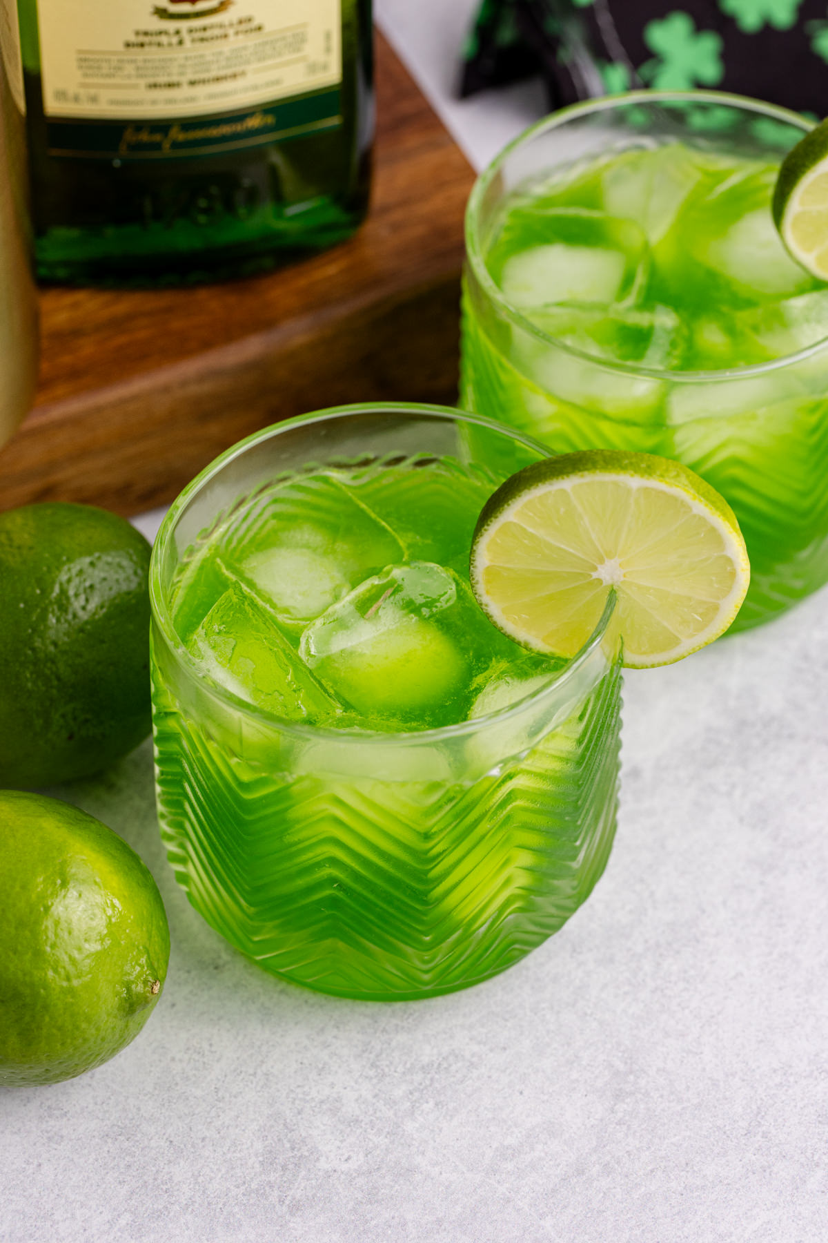 A glass filled with a cocktail and a lime on the rim.