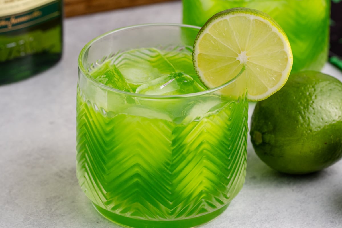 A Shamrock Sour on a table garnished with a slice of lime.
