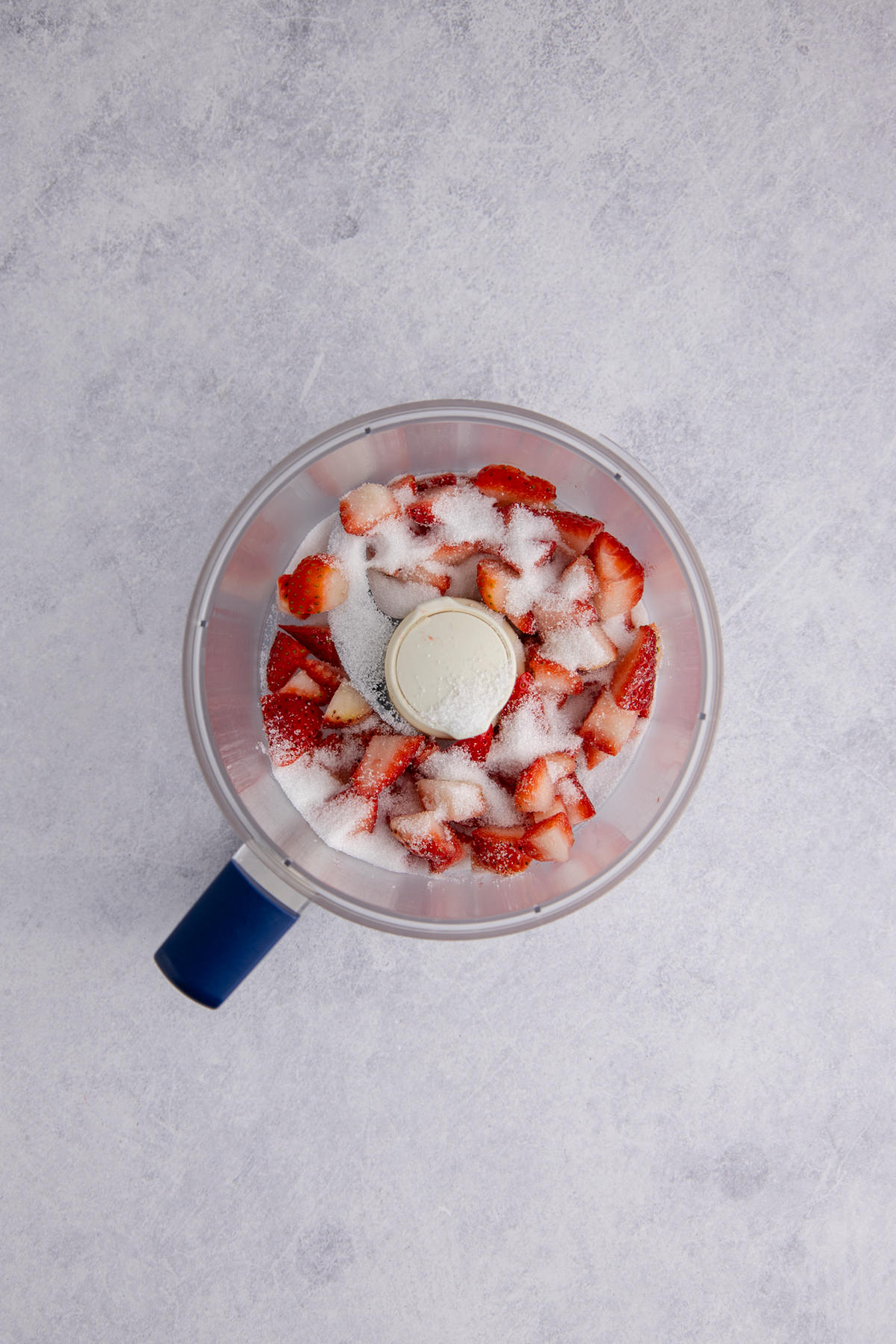 Strawberries and sugar in a food processor.