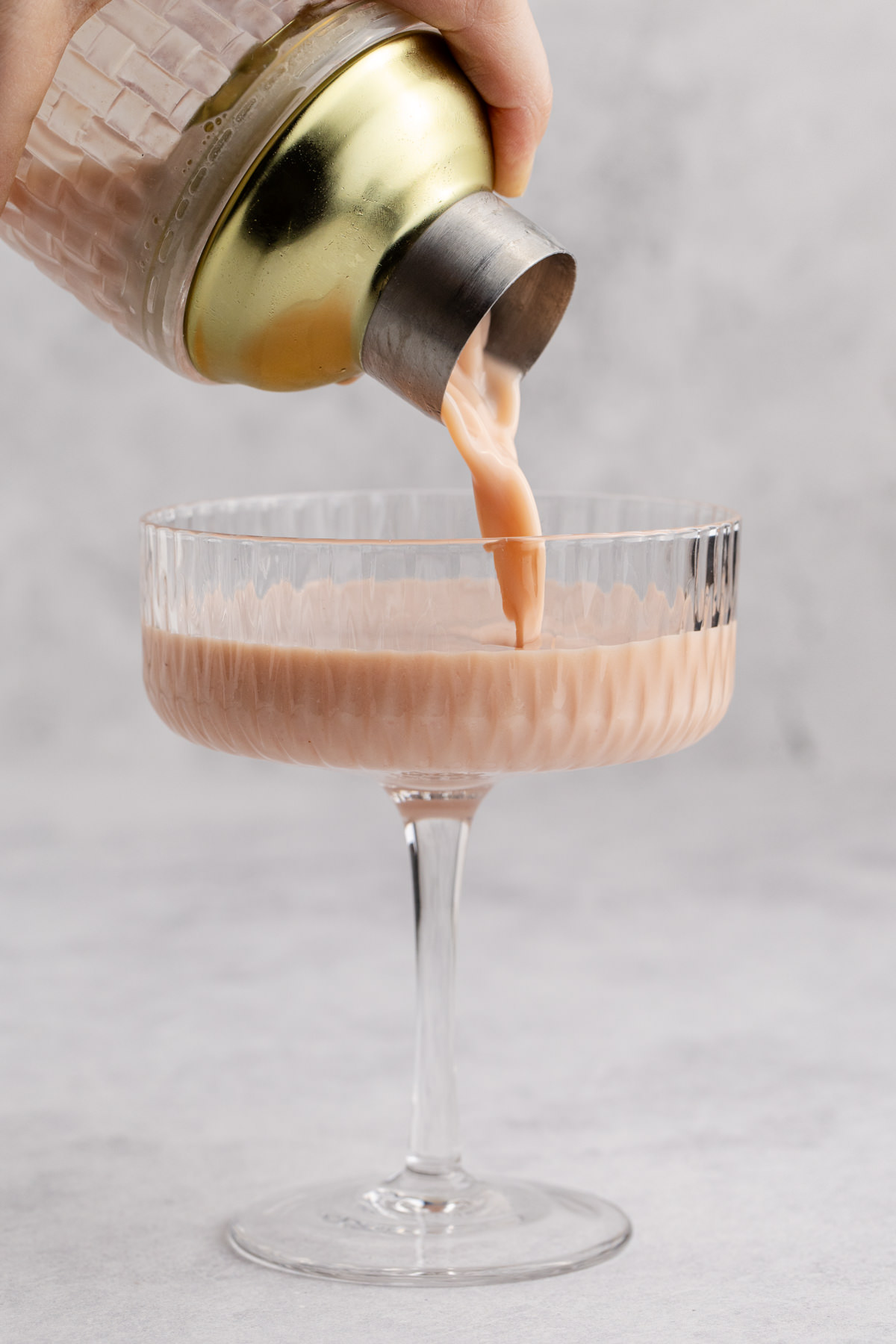 Drink being poured into a cocktail glass to serve.
