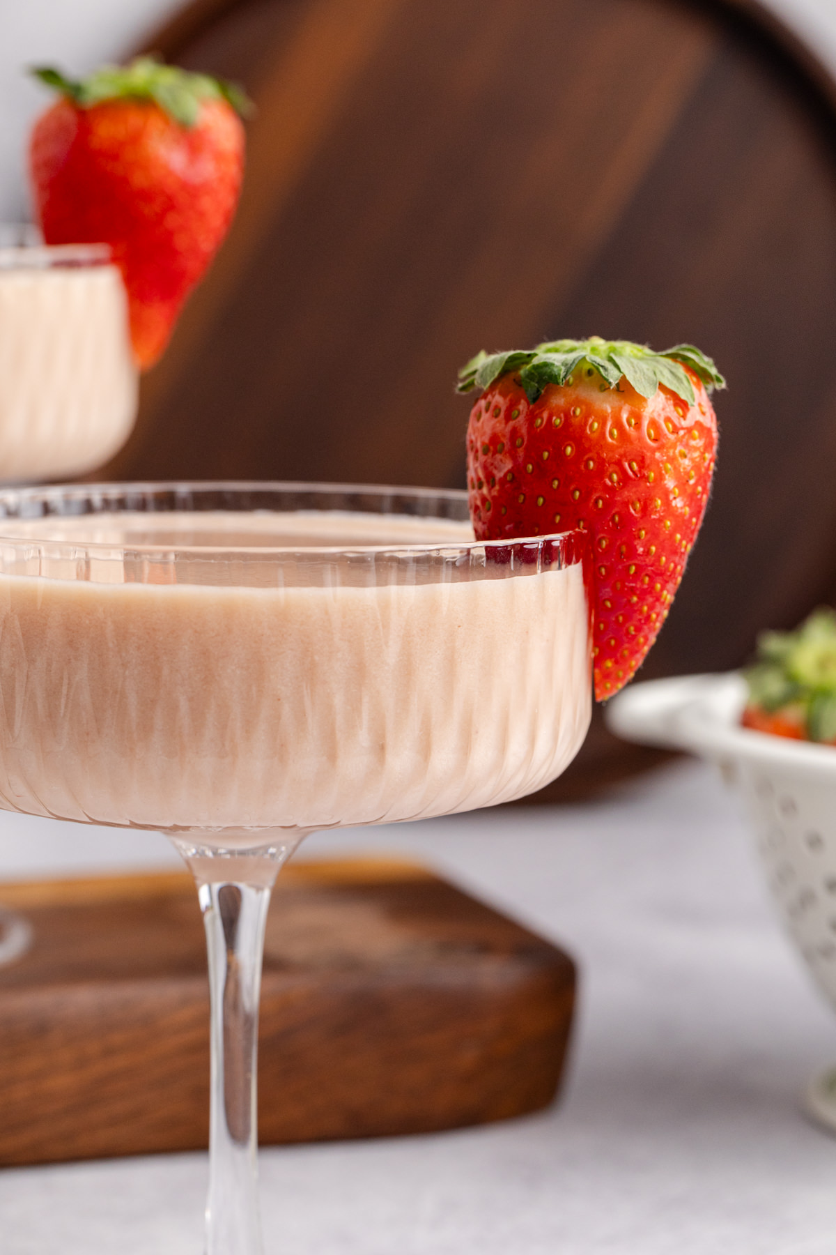 A martini with strawberries and cream in a cocktail glass.