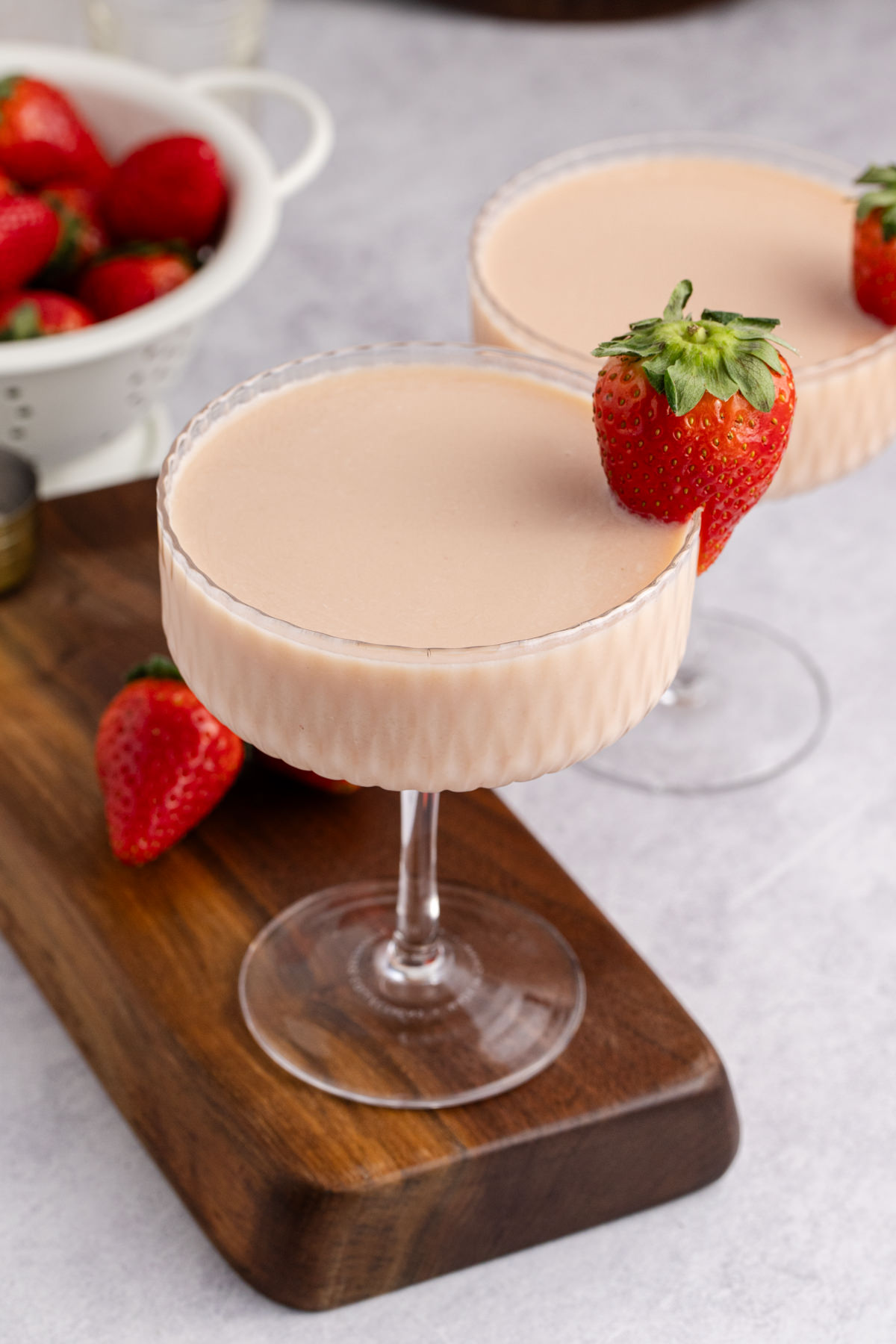 Two glassed filled with a martini and a strawberry garnish.
