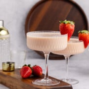 Strawberries and cream martini in a glass with a strawberry garnish.