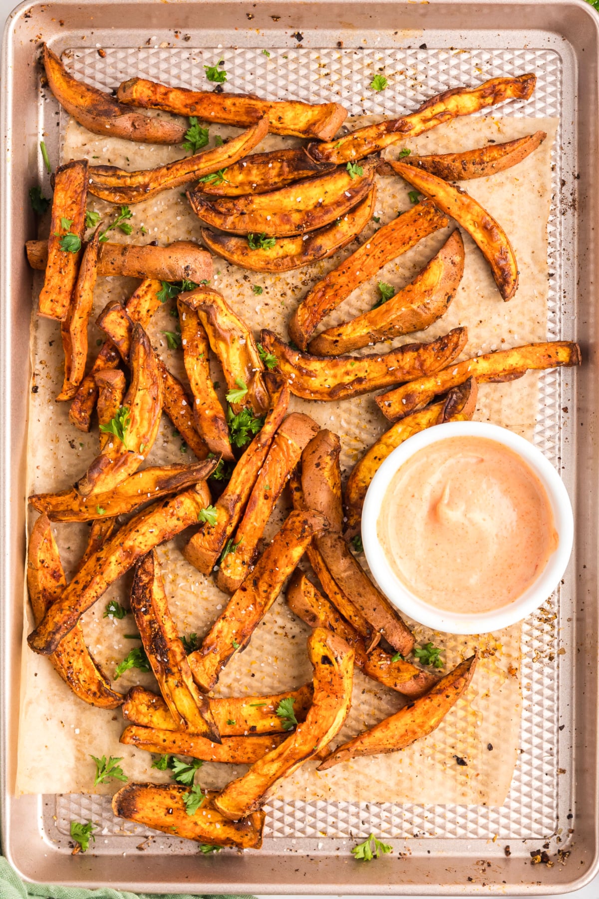 Sweet potato fries on a sheet pan with dipping sauce.
