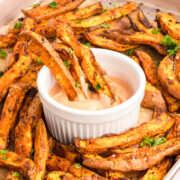 Oven-baked sweet potato fries being dipped into sauce.