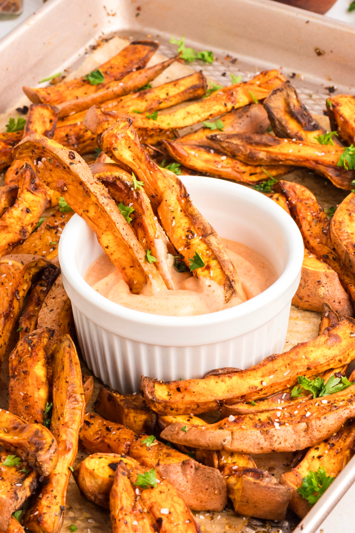 Sweet potato fries being dipped into dipping sauce.