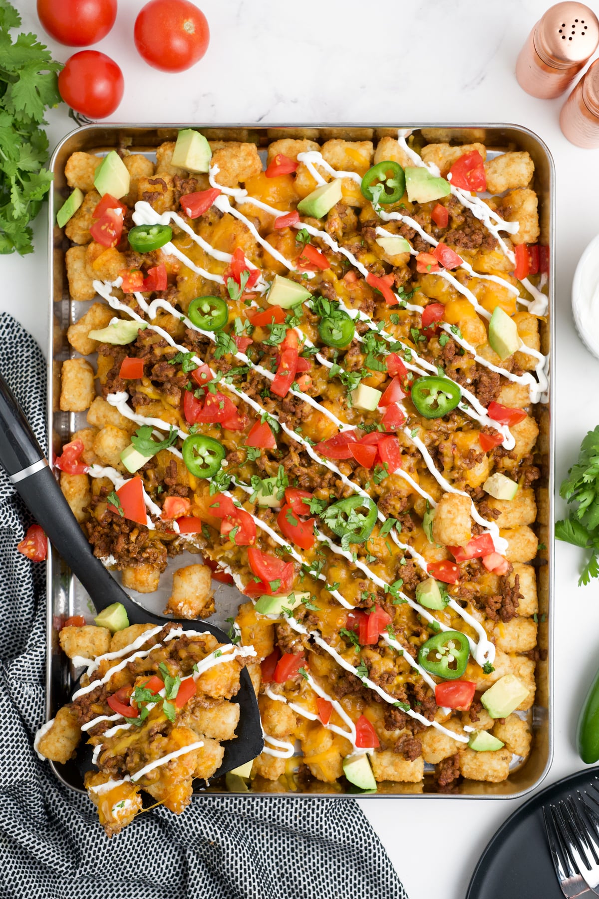 Totchos being scooped out of a sheet pan.