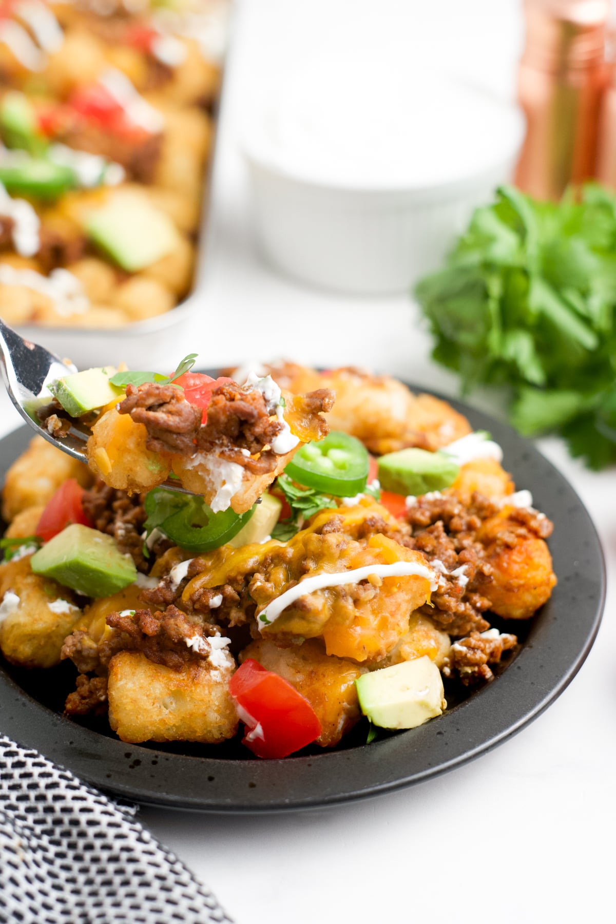 A fork scooping up some tater tot nachos.