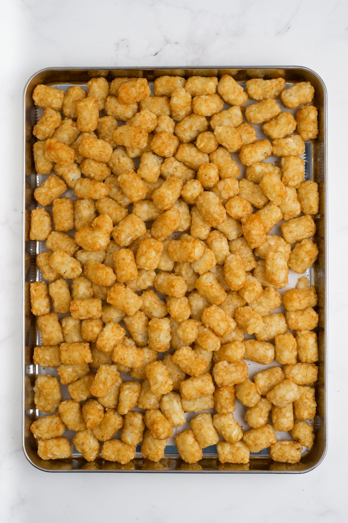 Tater tots on a sheet pan to cook.