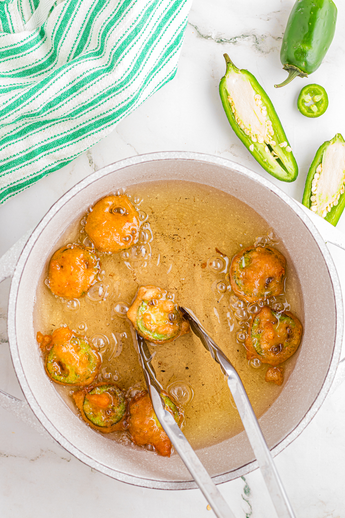 Frying the jalapeno slices in a deep pan.