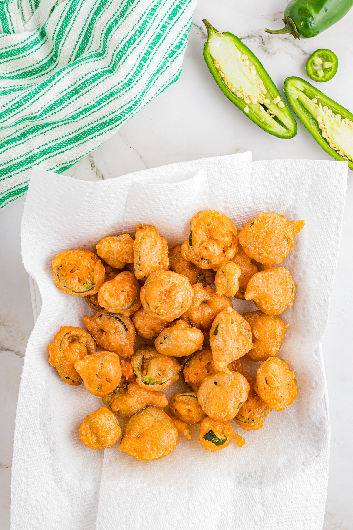 Finished jalapeno slices on a plate lined with paper towels.