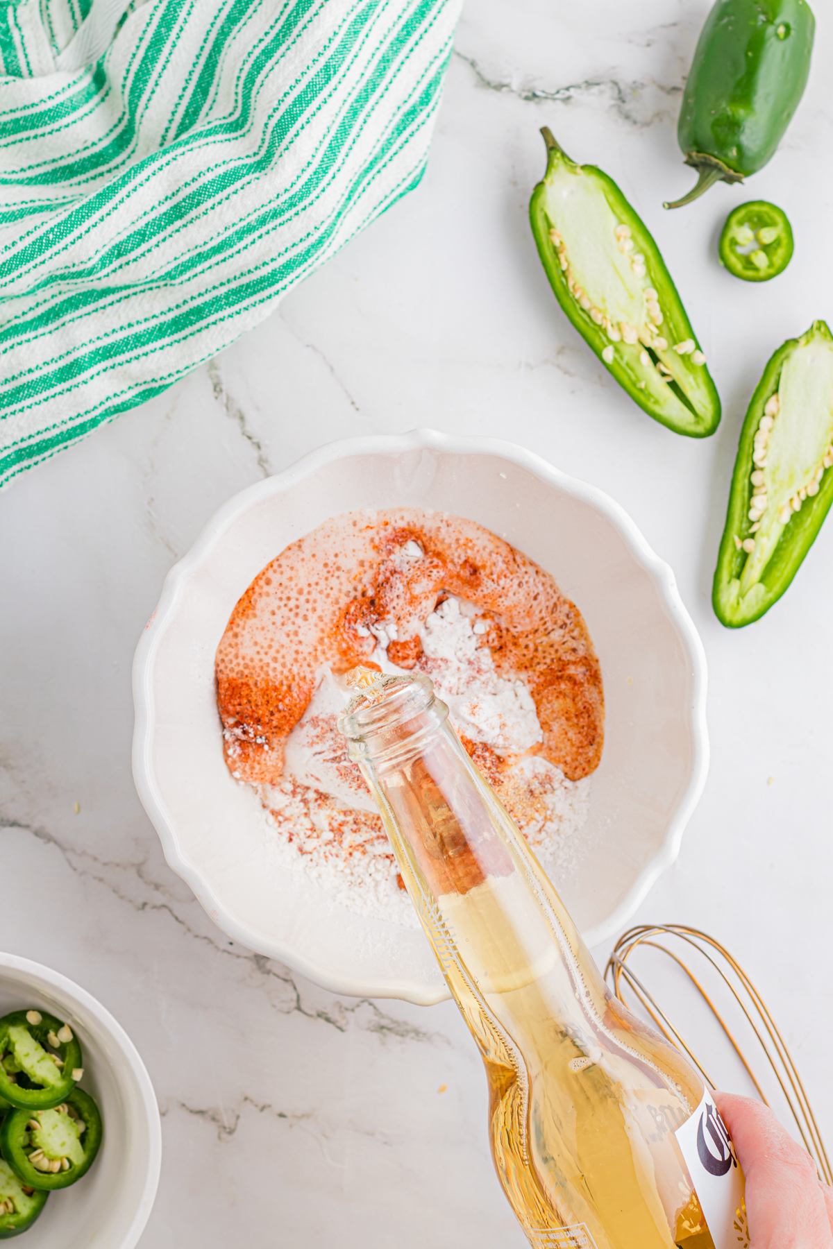 Beer being poured into a bowl with flour, spices, and baking powder.