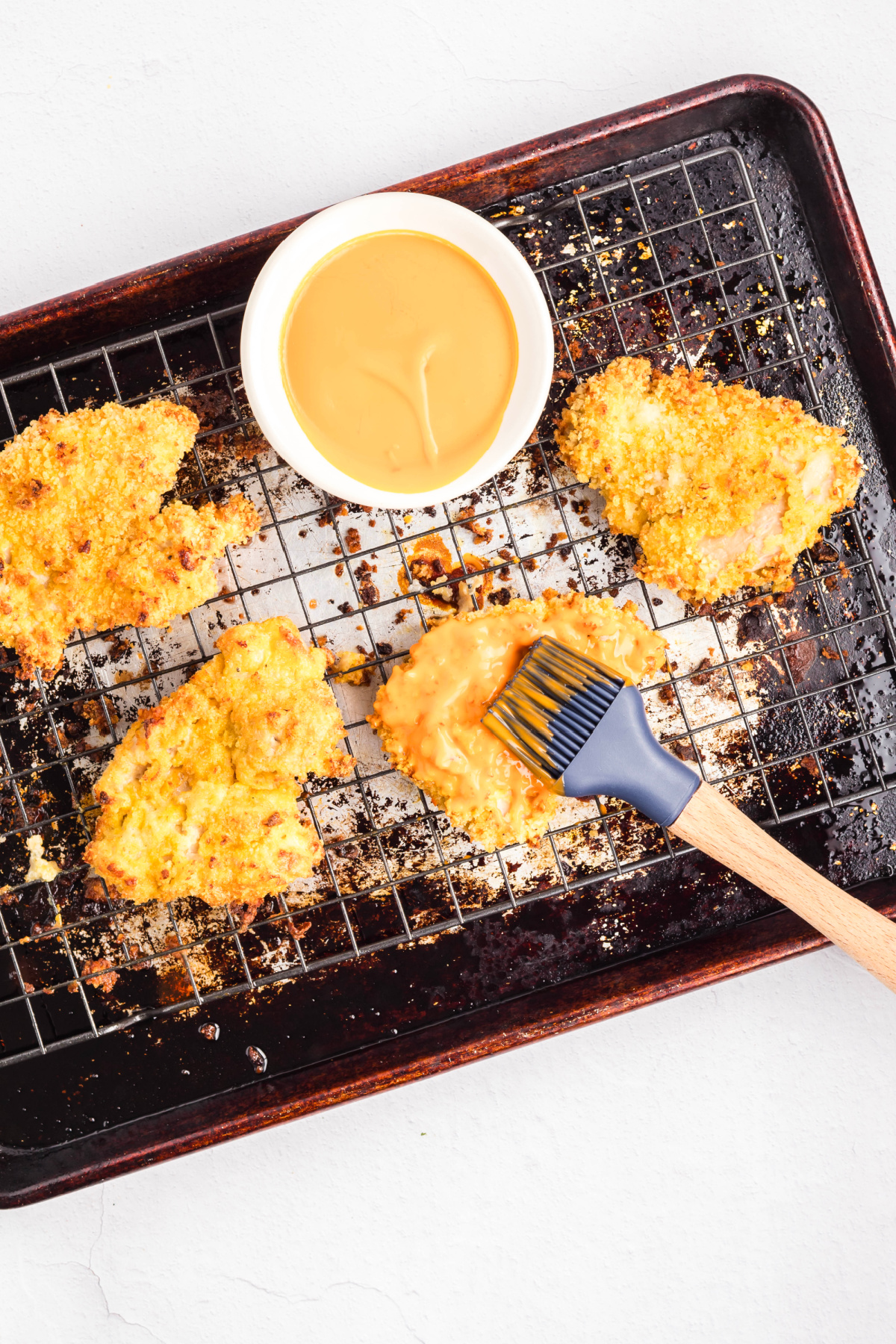 Chicken being coated in buffalo sauce.