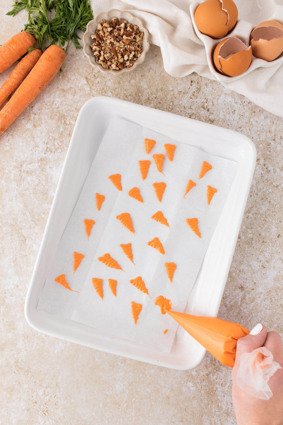 Candy melts in a piping bag and zigzag it onto a piece of parchment paper to make carrot shapes.