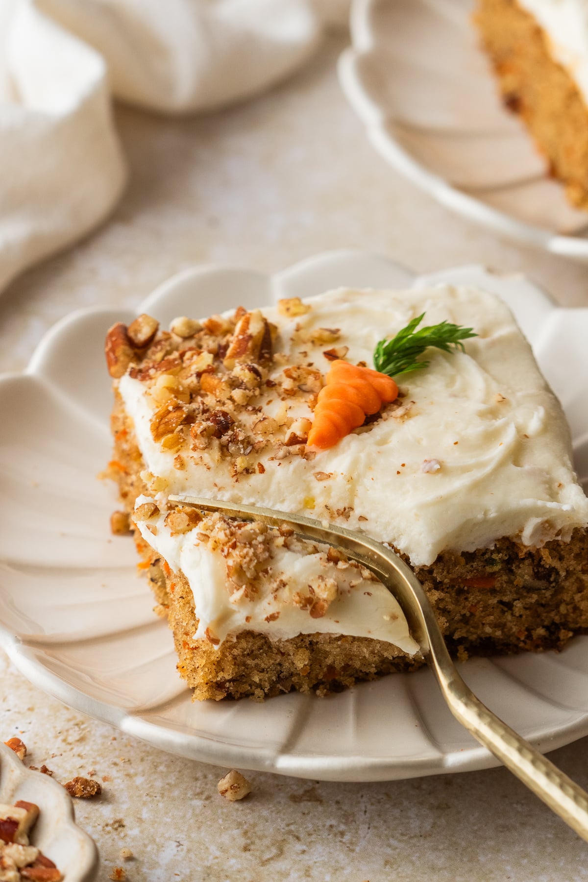 A fork taking a piece of carrot sheet cake off of the plate.