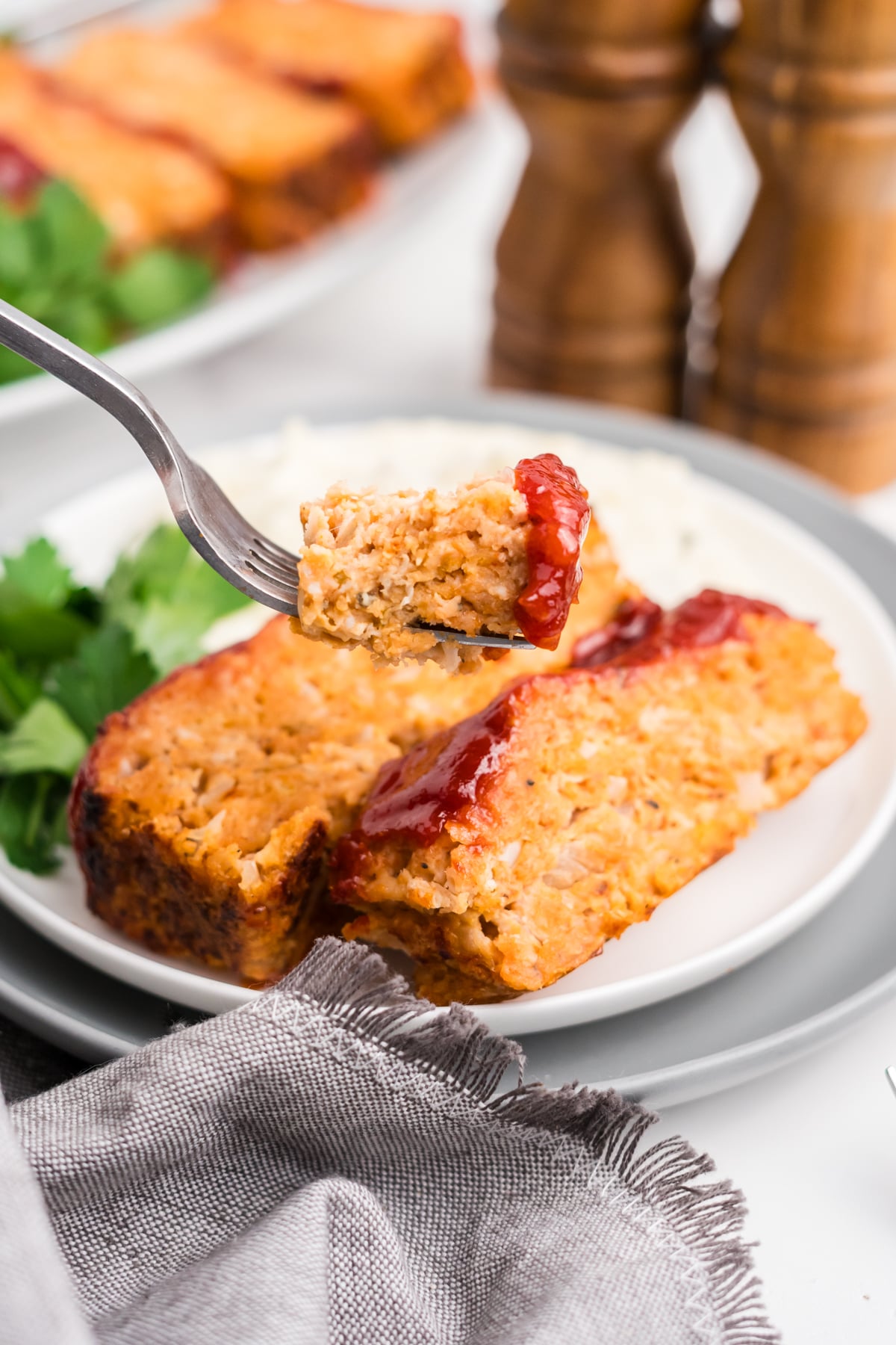 A fork holding up a slice of chicken meatloaf in the air.